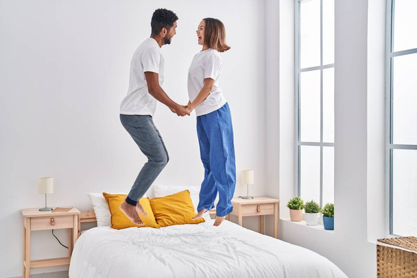 Mies ja nainen hymyilee luottavainen hyppäämällä sängyllä makuuhuoneessa - Valokuva, kuva