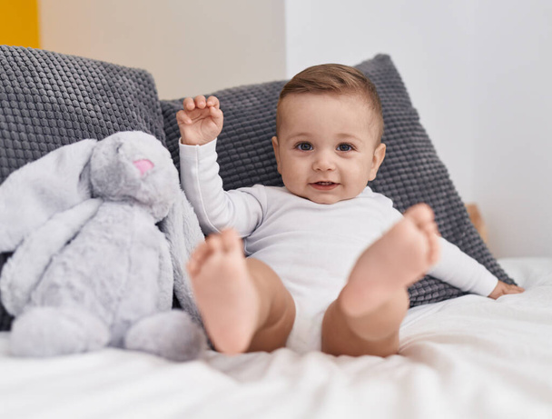 Adorable caucasian baby smiling confident sitting on bed at bedroom - Foto, afbeelding