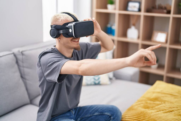 Genç beyaz adam evde sanal gerçeklik gözlüğü kullanıyor. - Fotoğraf, Görsel
