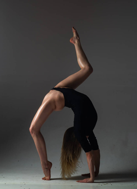 Flexible girl dancing. Beautiful flexible woman body. Fashion art studio portrait of fit sexy flexible woman on black. Gymnastic slim and flexible dancer woman performing. Stretches exercise - 写真・画像