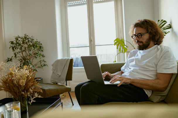 Empresário empresário sentado no sofá em casa e trabalhando no laptop on-line. Conceito de trabalho remoto - Foto, Imagem
