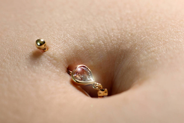 Female navel with jewelry. Piercing on the umbilicus. - Foto, Bild