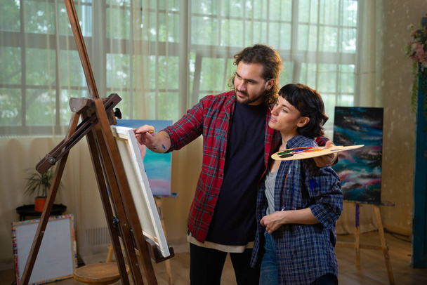 Mannen en vrouwen schilders werken samen in kunststudio op groot doek. Verf - Foto, afbeelding