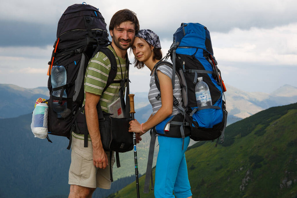 Una coppia affettuosa con zaini da escursionismo si trova di fronte alla fronte, profondamente innamorata, sullo sfondo delle montagne dei Carpazi - Foto, immagini