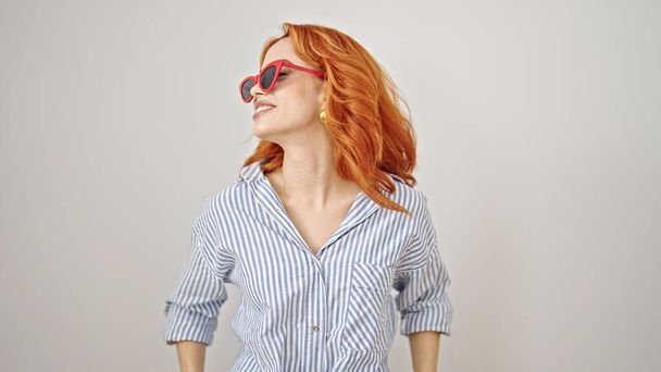 Fiatal vörös hajú nő visel napszemüveg néz oldalra elszigetelt fehér háttér - Fotó, kép