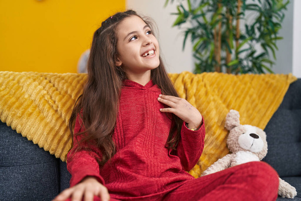 Adorável menina hispânica sorrindo confiante sentado no sofá em casa - Foto, Imagem