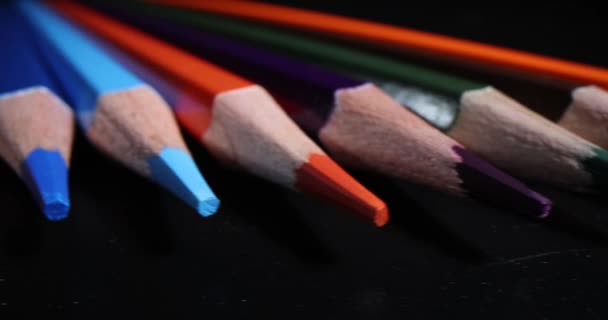Špičaté pestrobarevné hroty tužek na tmavém pozadí. Tužky pro kreslení a studium - Záběry, video