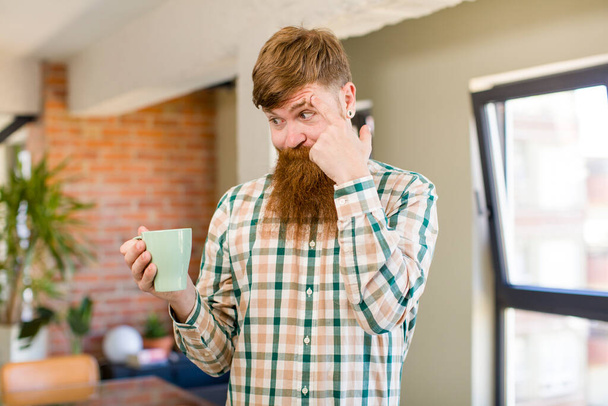 red hair man red hair man looking surprised, realizing a new thought, idea or concept with a coffee mug - 写真・画像