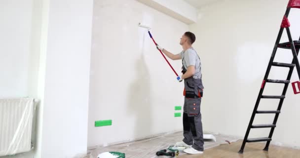 Maler bemalt Wohnungswand mit Rollerpinsel in weiß. Malerreparatur und Heimwerker - Filmmaterial, Video