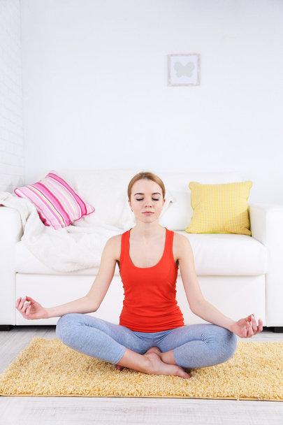 Young woman doing yoga at home - Фото, изображение