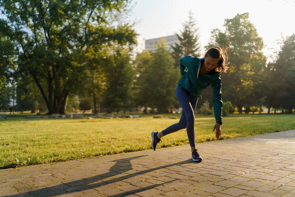 Full lenght portrait of beautiful fitness woman doing running drills in the city park. Workout at the park. Outdoor workout concept. - Foto, Imagem