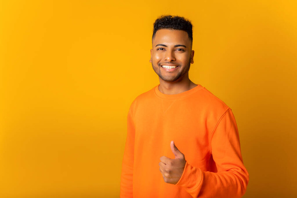 Portrait of indian man standing with thumb up, like gesture, demonstrating approval and agree with suggestion. Indoor studio shot isolated on orange background - Фото, зображення