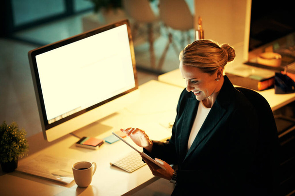 У меня есть инструменты, чтобы обойти все сроки. зрелая женщина, использующая свой цифровой планшет во время работы допоздна в офисе - Фото, изображение