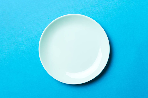 Top view of isolated of colored background empty round blue plate for food. Empty dish with space for your design. - Foto, Imagem
