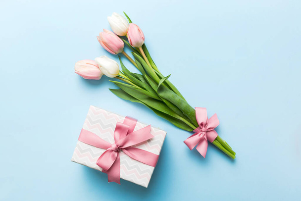 Pink tulips flowers and gift or present box on colored table background. Mothers Day, Birthday, Womens Day, celebration concept. Space for text top view. - Fotografie, Obrázek