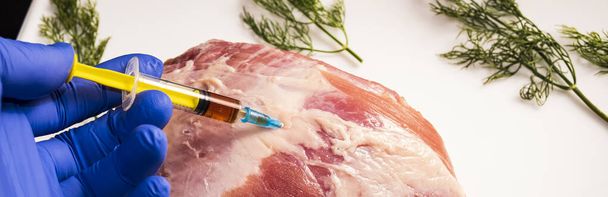 Injection from a syringe into raw meat on a dark background.Conceptual illustration of hormones and antibiotics in food production. - Photo, image