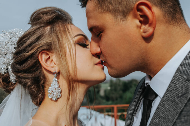 the bride and groom against the background of the sky. Royal wedding concept. The groom kisses the bride's hand. Tenderness and calmness. Portrait photography - Foto, Imagen