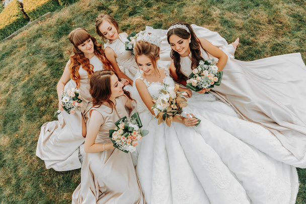 Photo of the bride and bridesmaidswith wedding bouquets. Wedding day. Happy girls at their best friend's wedding. Beautiful bride with her friends. Summer wedding - Foto, Imagem