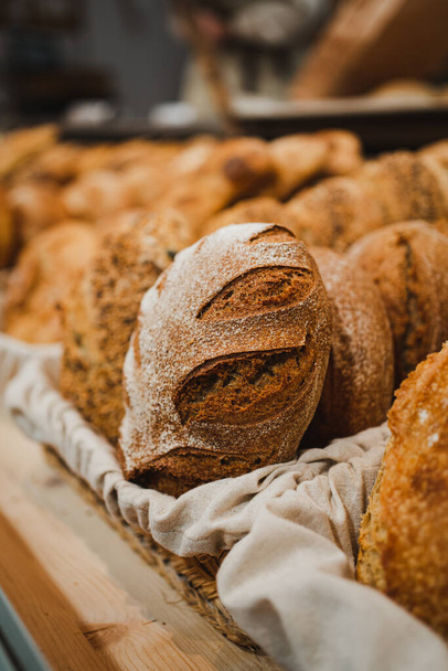 Krustiges Brot mit Mehl darauf in einem rustikalen Korb in einer Bäckerei - Foto, Bild