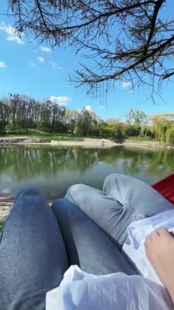 ζευγάρι που βρίσκεται σε αιώρα στο πάρκο της πόλης κοντά στη λίμνη pov view - Πλάνα, βίντεο
