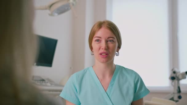 Un ginecólogo habla con un paciente durante una consulta médica en una clínica moderna en el consultorio ginecológico - Metraje, vídeo