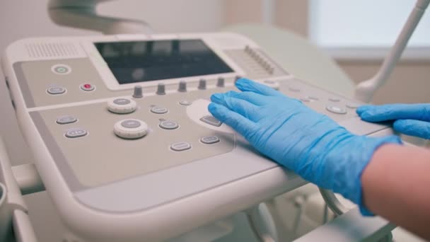 Um ginecologista usa um dispositivo de ultra-som transvaginal pressiona botões tira uma foto dos órgãos internos do paciente em close-up clínica - Filmagem, Vídeo