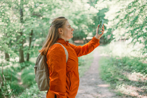 Angry woman tourist hiker hand holding smart phone searching signal in the forest. Communication, cellular problem, bad connection. No signal cellphone network. No communication coverage, lost contact - Foto, afbeelding