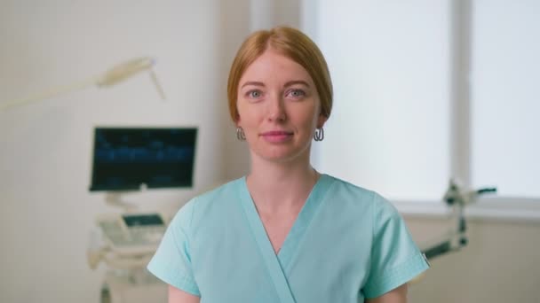médico ginecólogo sonriente en el consultorio ginecológico cerca de ultrasonido y silla ginecológica esperando pacientes - Imágenes, Vídeo