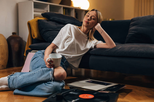Woman enjoying music alone in the living room. - Valokuva, kuva