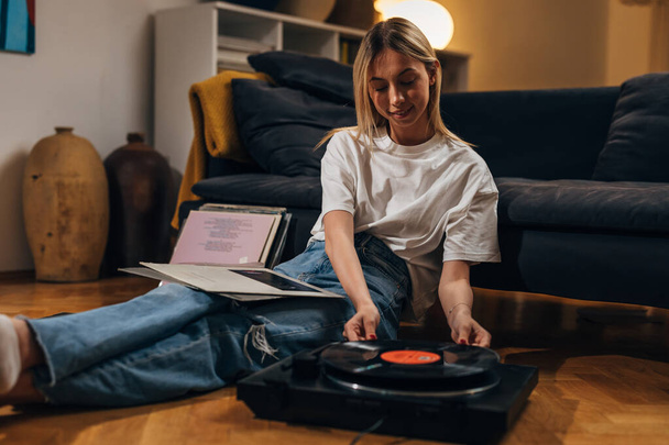 Young woman enjoys evenings with music played on gramophone. - Foto, afbeelding