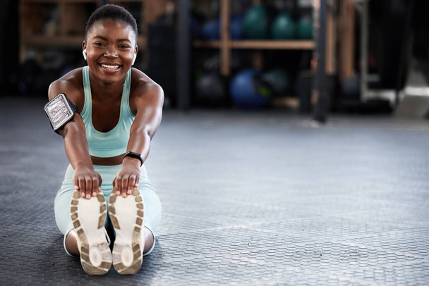 Μουσική, πορτραίτο ή χαρούμενο κορίτσι σε γυμναστήριο που τεντώνει τα πόδια για γυμναστική ή σωματική κίνηση με ήχο. Streaming ραδιόφωνο, ακουστικά ή μαύρη γυναίκα χαμογελώντας στην προπόνηση προθέρμανση για ευελιξία. - Φωτογραφία, εικόνα