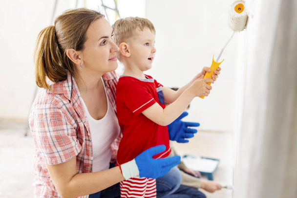 Famiglia felice madre e figlio figlio dipingere il muro con vernice con rullo e pennello. Riparazione in appartamento - Foto, immagini