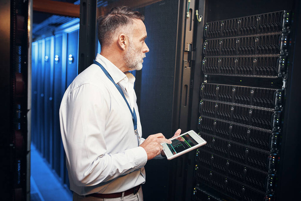 It support are the unsung heroes. a mature man using a digital tablet while working in a server room - Photo, Image