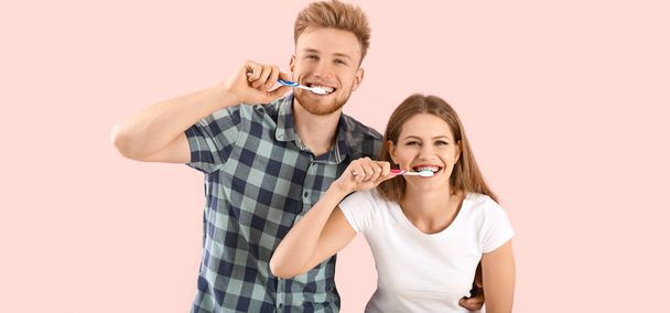 Happy couple brushing teeth on pink background - Фото, зображення