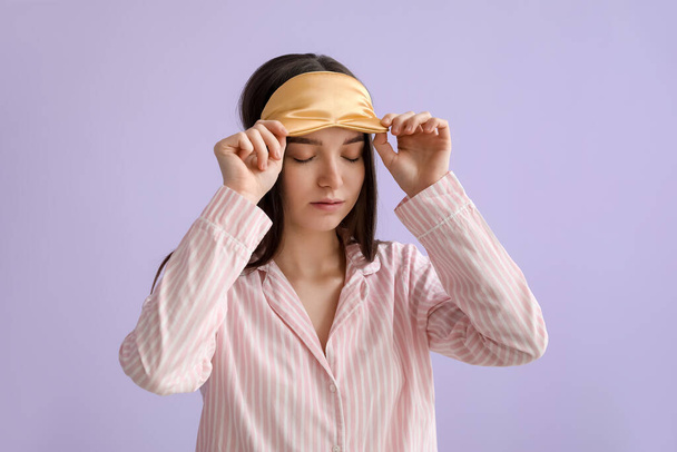 Young woman with sleeping mask on lilac background - Foto, Bild