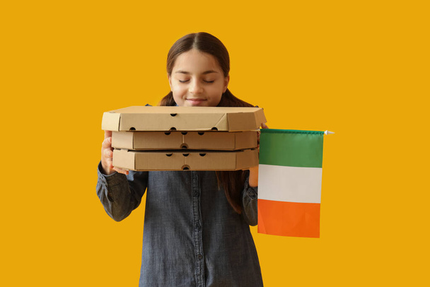 Niña con bandera de Italia y cajas de sabrosa pizza sobre fondo amarillo - Foto, imagen