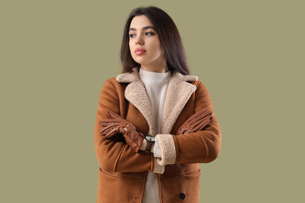 Stylish young woman in leather gloves on green background - Photo, Image