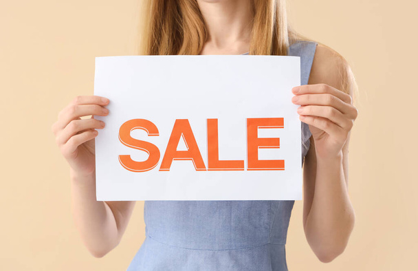 Young woman with sale sign on beige background, closeup - Фото, зображення