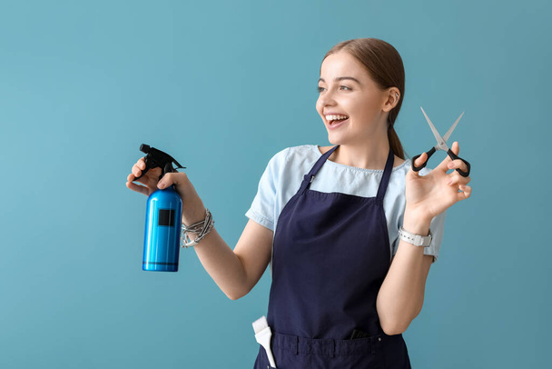 Coiffeur féminin avec ciseaux et spray sur fond bleu - Photo, image