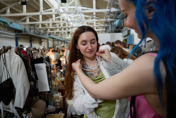 LGBT couple buying fashion accessories at a flea market. Two young lesbian women shopping. Portrait of a cheerful diverse women buying vintage stuff in a thrift shop - Fotó, kép