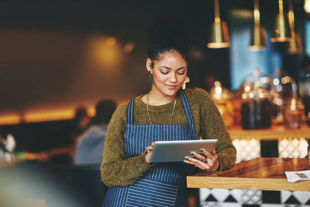 Ihren Coffeeshop auf die Social-Media-Landkarte setzen. eine junge Frau, die während ihrer Arbeit in einem Café ein digitales Tablet benutzt - Foto, Bild