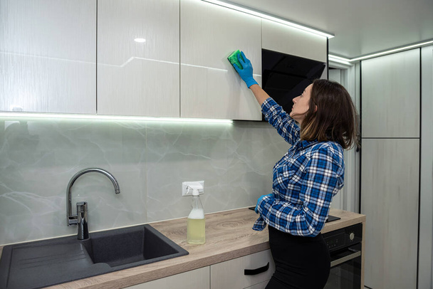 beautiful young woman is cleaning while smiling while doing this in a modern kitchen. cleaning is a joy. the woman cleans. clean house - Foto, Imagen