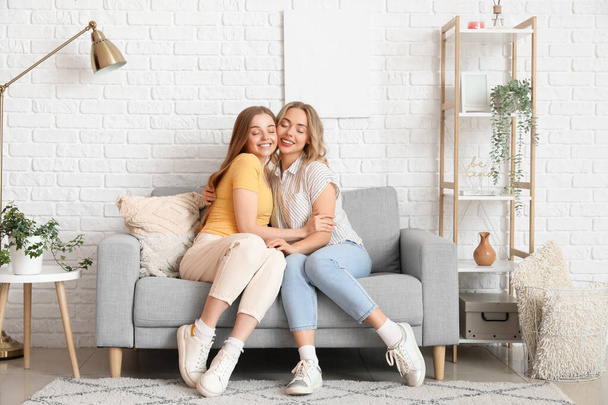 Junge Schwestern umarmen sich zu Hause auf dem Sofa - Foto, Bild