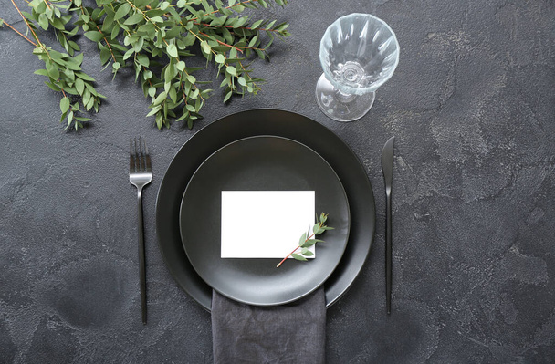 Stylish table setting with blank card and glass on grunge black background - Photo, Image