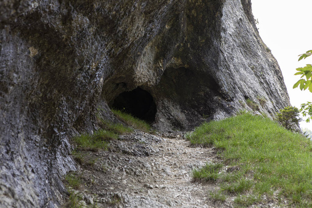 A Jura-hegység barlangjának bejáratához vezető út. Fekete üreges szikla. Hegyi alagút túraútvonal, barlang belép a sötét folyosón, Gorges de Court, Svájc - Fotó, kép