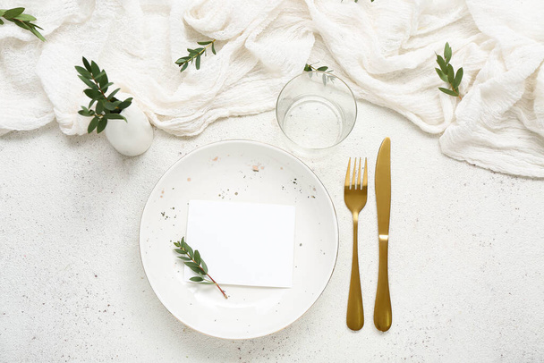 Тарелка с золотыми столовыми приборами и пустой карточкой на белом фоне гранжа - Фото, изображение