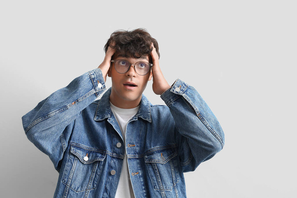 Überraschter junger Mann mit stylischer Brille auf hellem Hintergrund - Foto, Bild