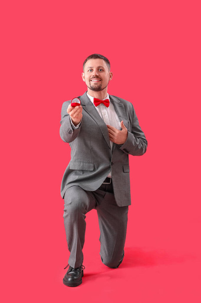 Handsome man with engagement ring on red background - Φωτογραφία, εικόνα