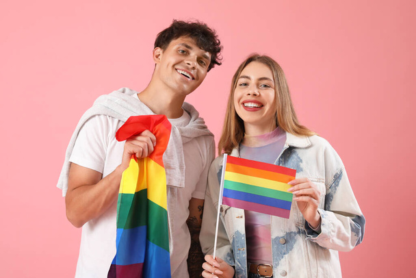 Young couple with LGBT flags on pink background - Фото, изображение