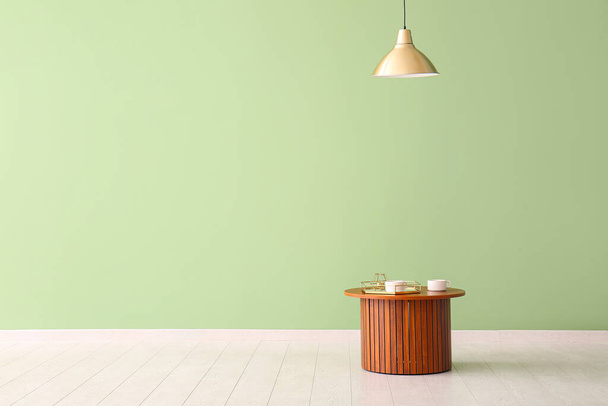 Mesa de centro de madera con bandeja y tazas cerca de la pared verde - Foto, imagen